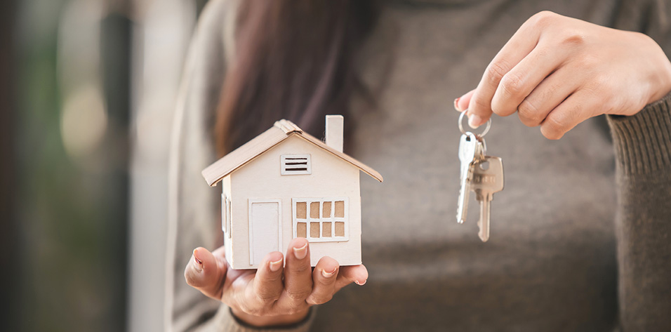 Woman holding a key and an miniature house